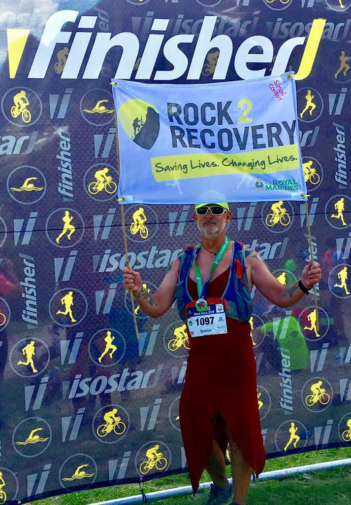 Simon Conroy wearing his dress and holding a Rock 2 Recovery sign at 2019 Marathon du Mont Blanc (Photo: Doug Mayer)