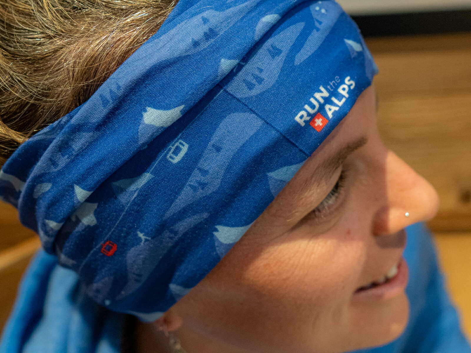 Lady with wearing a Run the Alps Mountain Design Buff as headband