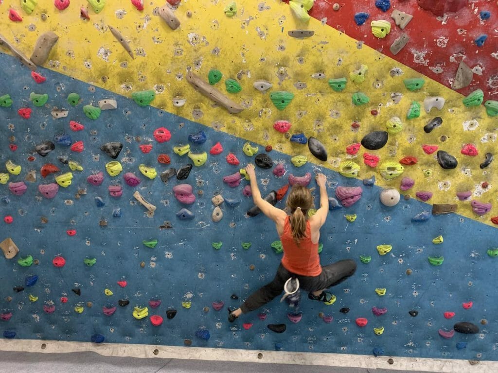 Heather Ohly bouldering on a blue, yellow and red wall