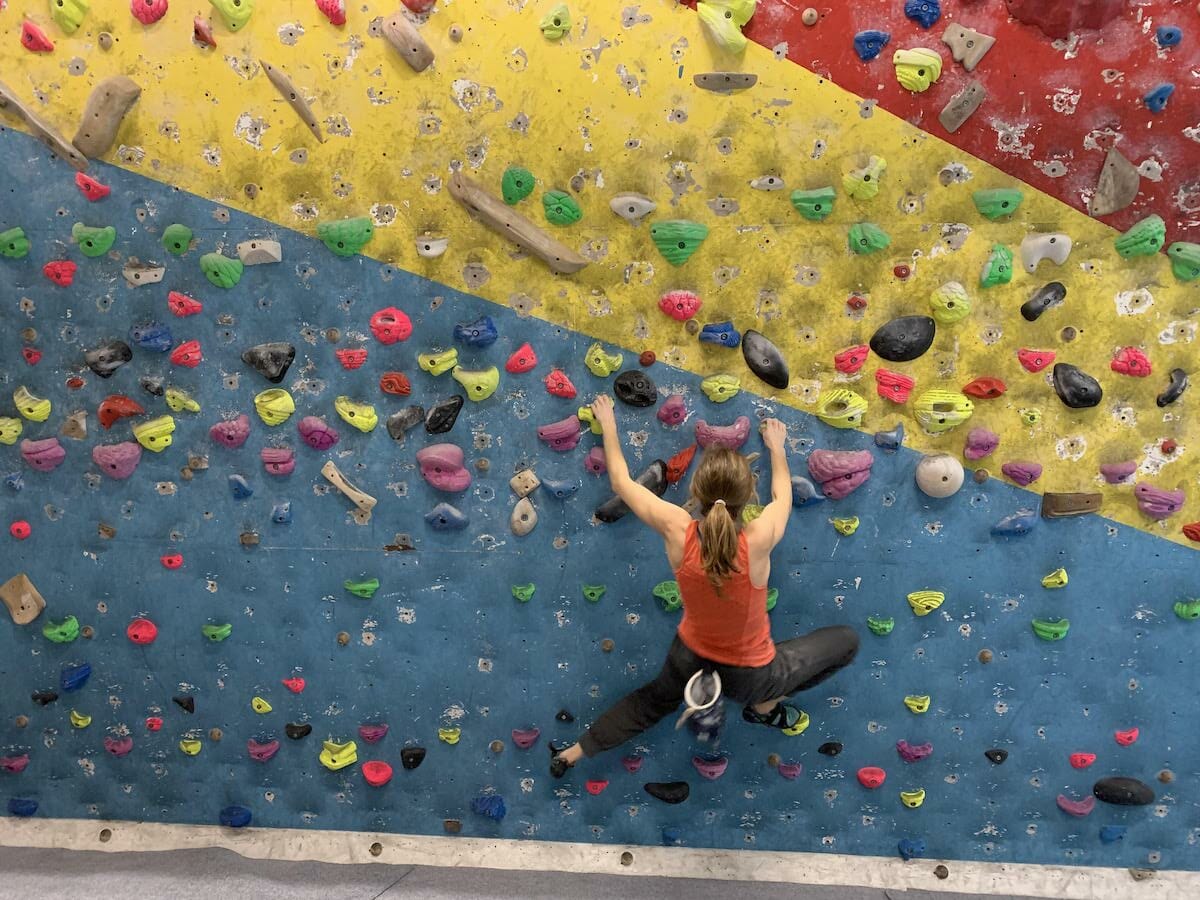 Heather Ohly bouldering on a blue, yellow and red wall