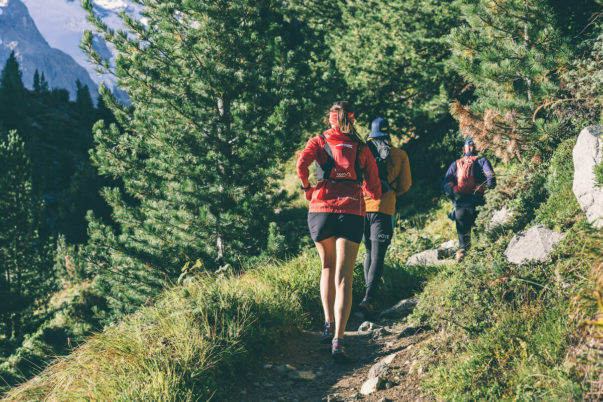 Trail runners on a single track in a forested valley
