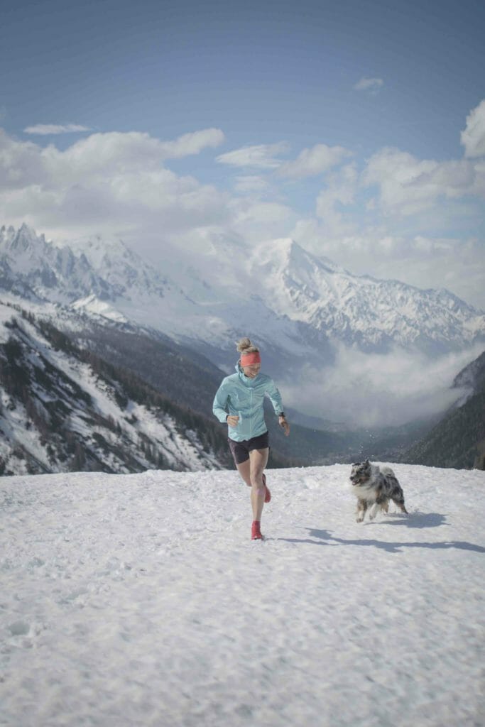 Mimmi Kotka in shorts running on snow with her dog