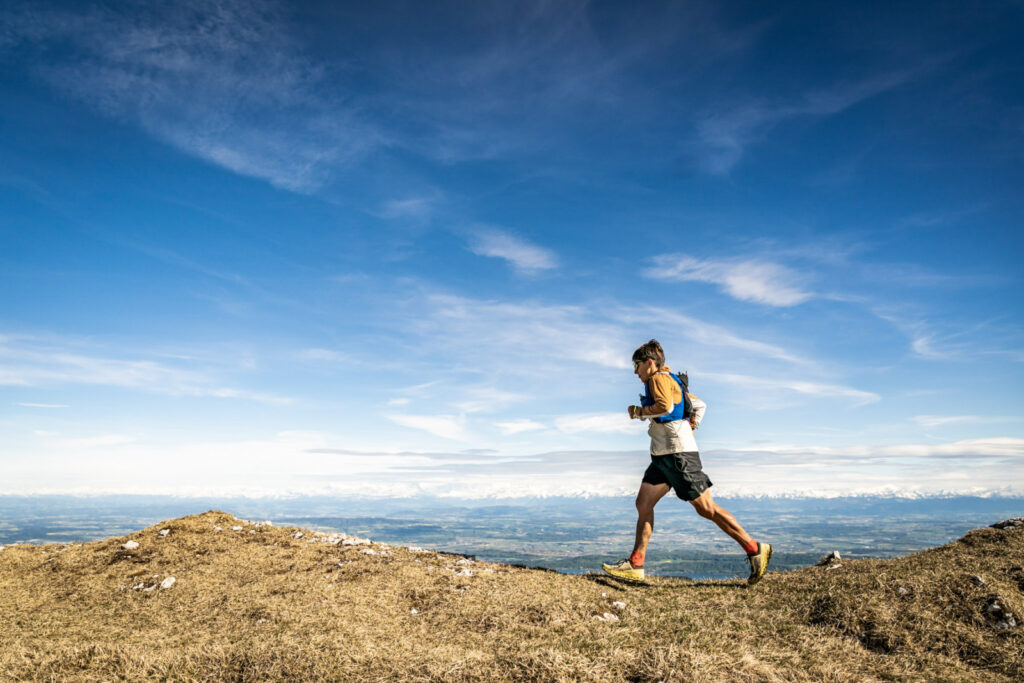 Xavier Thévenard running along the crest of the Jura mountains with the Alps in the distance.