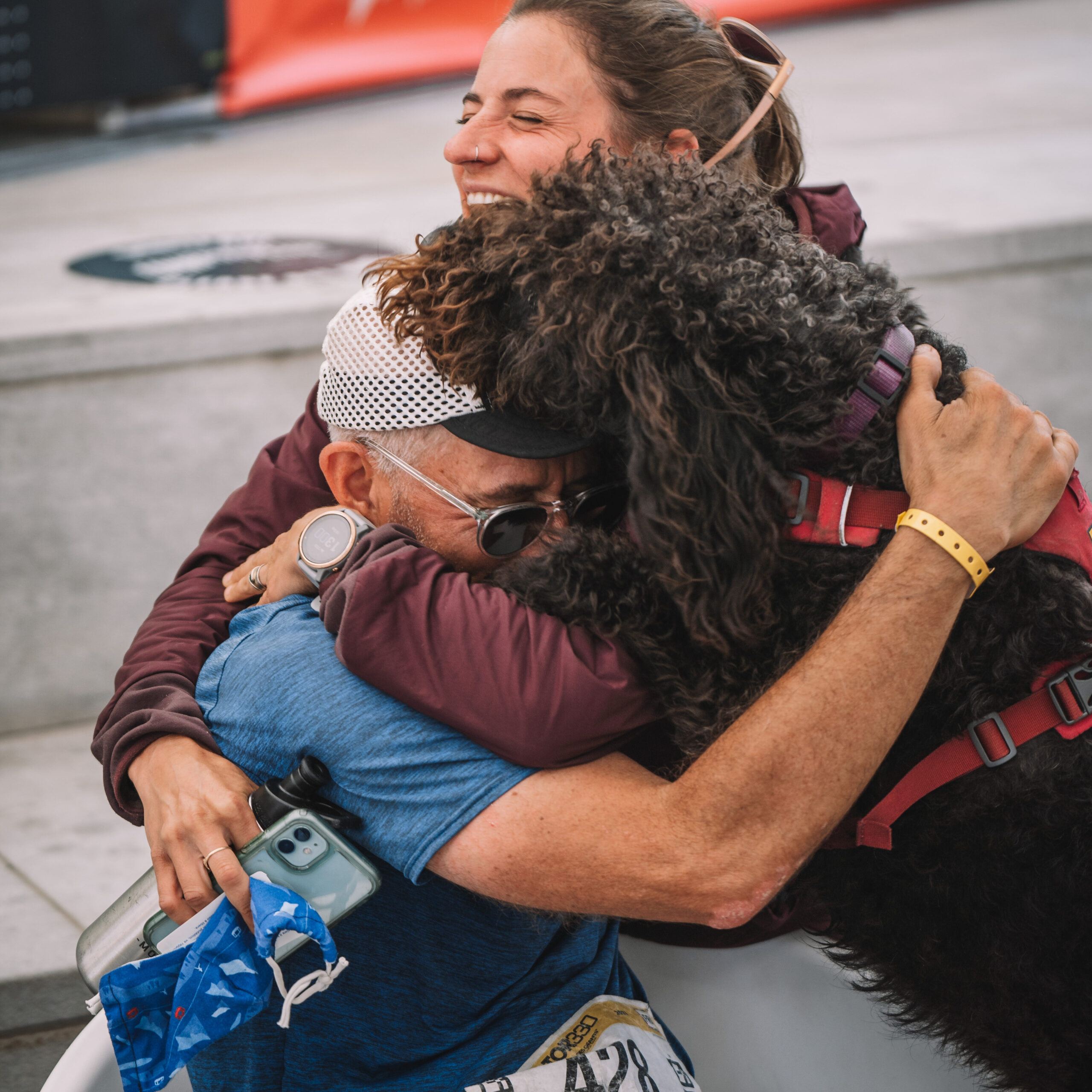 Trail runner Doug Mayer, labradoodle and spectator Hillary Geraldi in a group hug